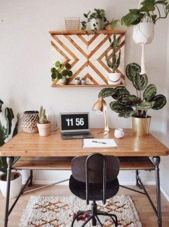 Brīnišķīgs boho stila mājas birojs ar retro koka galdu, boho paklāju.